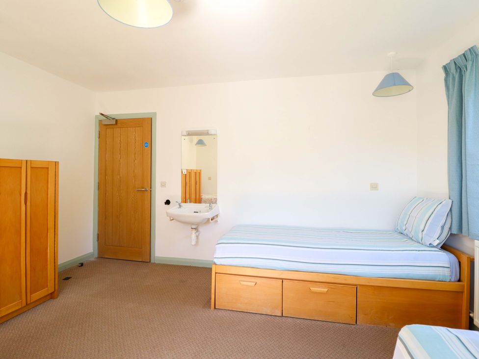 A bedroom with two beds and a wardrobe at Clwyd Special Riding Centre in Llanfynydd