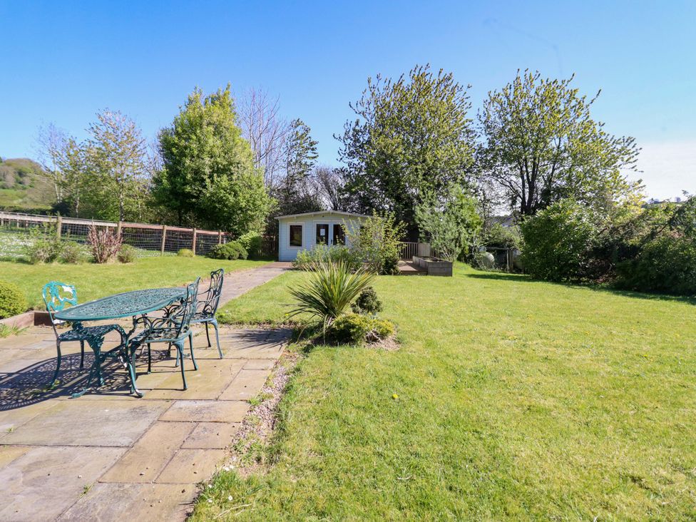 A garden with seating, a shed, and trees at Clwyd Special Riding Centre in Llanfynydd