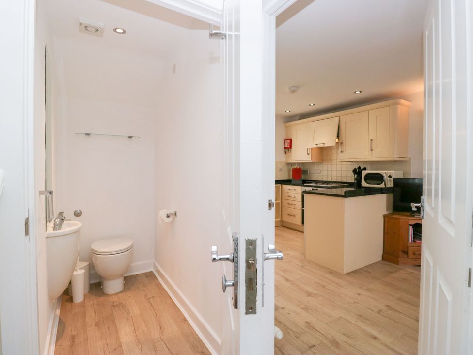 A bathroom with a toilet and sink leading to a kitchen at Swirl Howe in Keswick