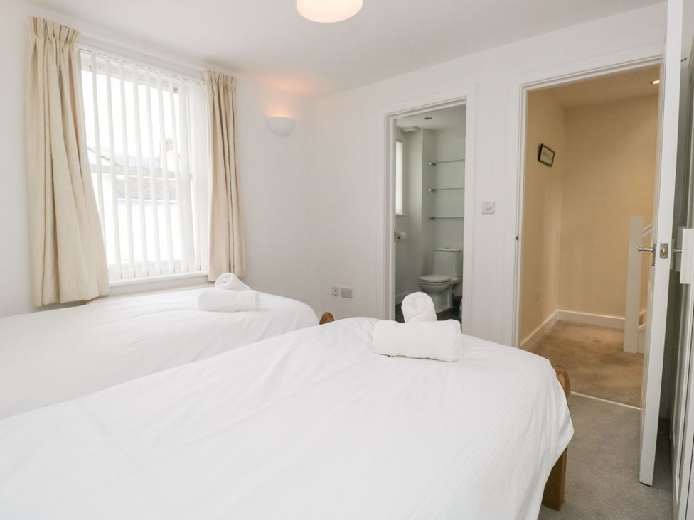 A bedroom with two beds and a door to a bathroom at Swirl Howe in Keswick