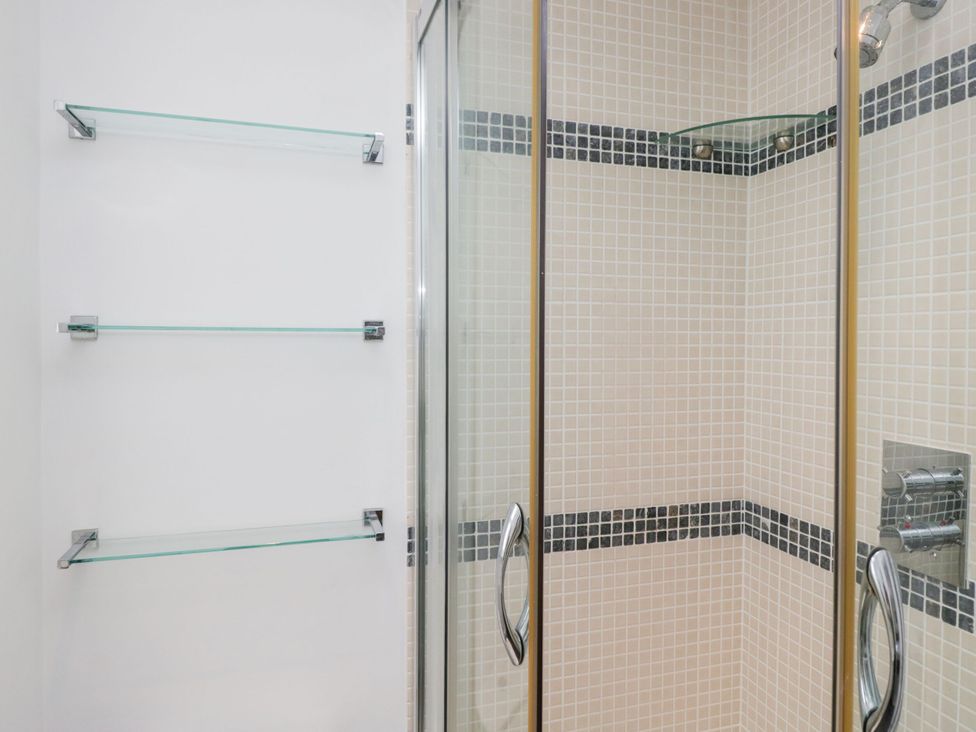 A shower with glass doors and shelves in a bathroom at Swirl Howe in Keswick