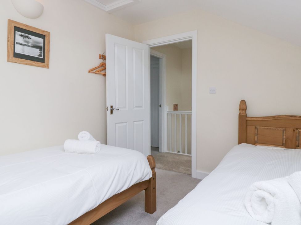 A bedroom with two beds and a doorway at Swirl Howe in Keswick