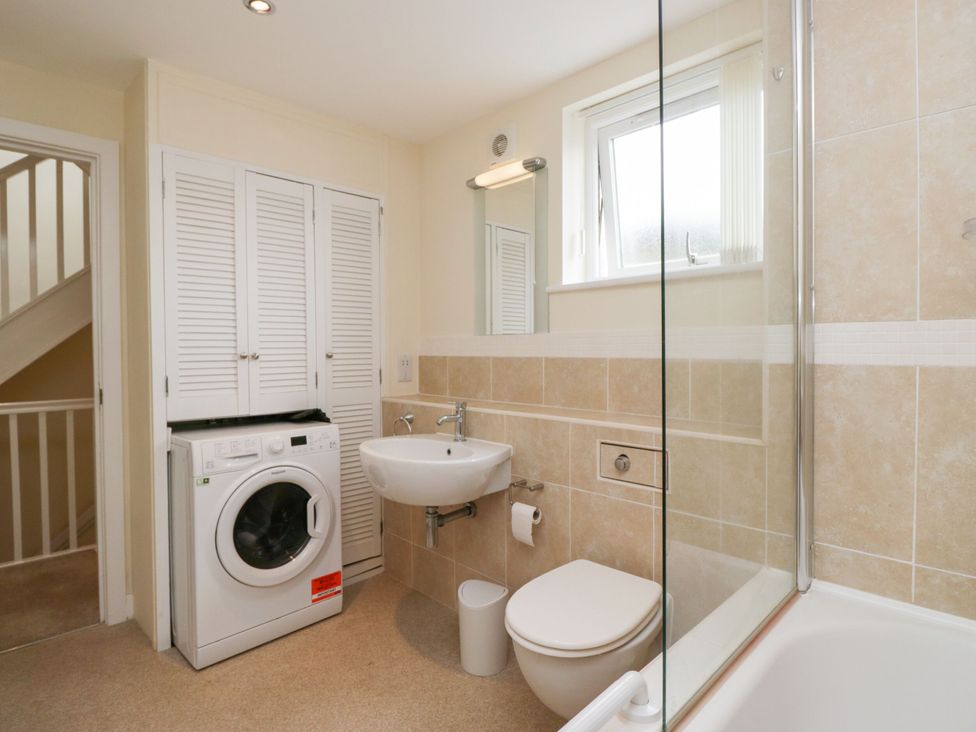 A bathroom featuring a washing machine, sink, toilet, and shower at Swirl Howe in Keswick