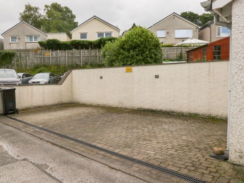A paved area with a garbage bin and cars in the background at Swirl Howe in Keswick
