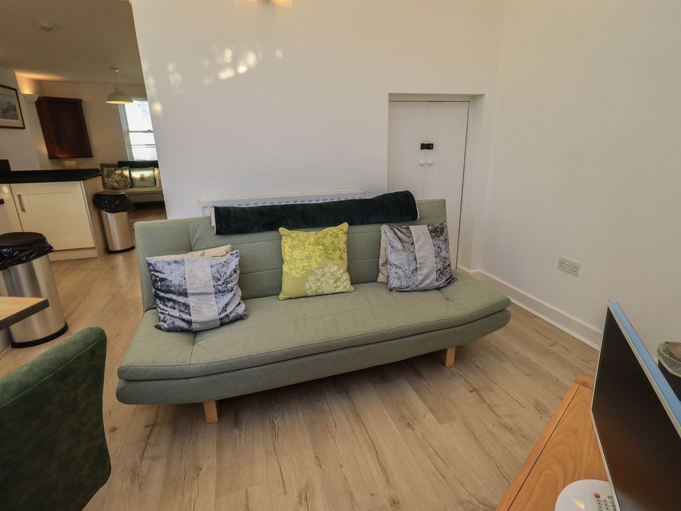 A living room with a sofa and television at Swirl Howe in Keswick