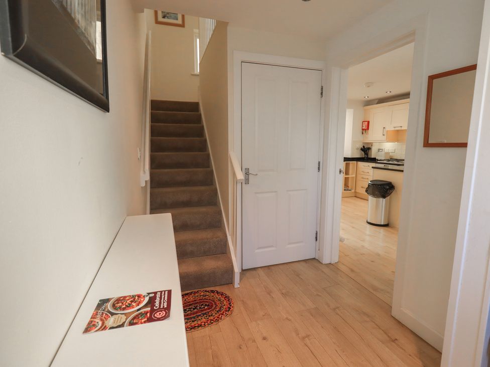 A hallway with a staircase and a kitchen door at Swirl Howe in Keswick