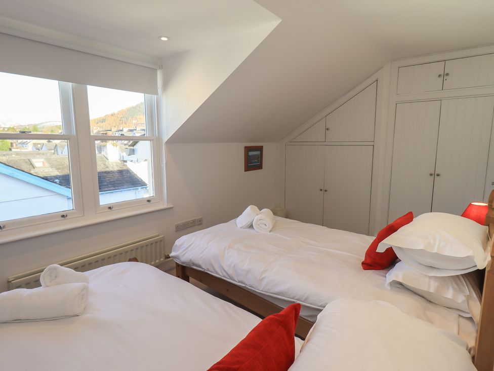 A bedroom with two beds and a wardrobe at Swirl Howe in Keswick