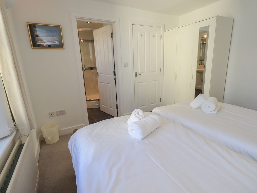 A bedroom with two beds and a wardrobe at Swirl Howe in Keswick