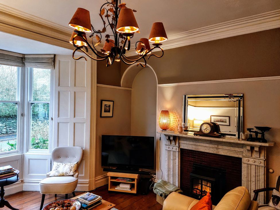 A living room with a chandelier, television, and fireplace at 1 Park Road in Windermere