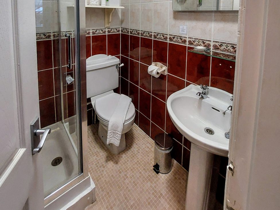 A bathroom with a shower, toilet, sink and mirror at 1 Park Road in Windermere