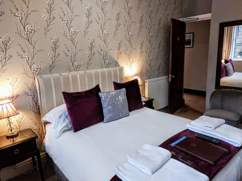 A bedroom with a bed, pillows, and a nightstand at 1 Park Road in Windermere