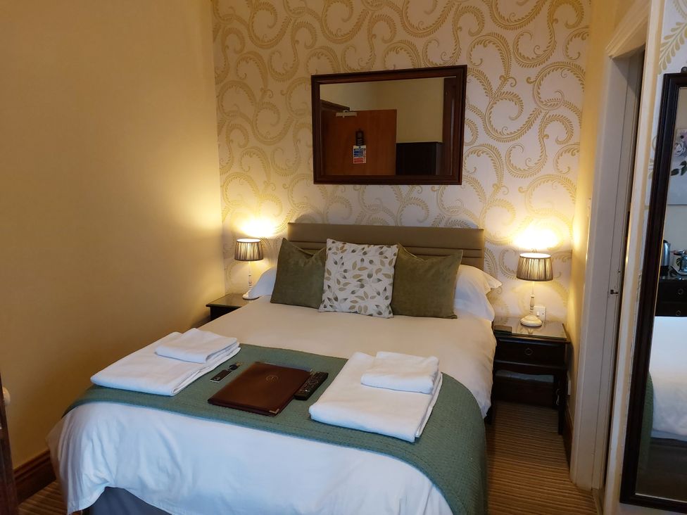 A bedroom with a bed and nightstands at 1 Park Road, Windermere