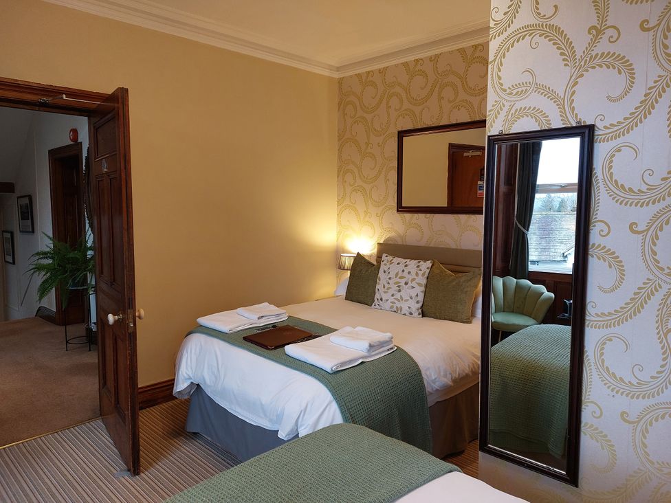 A bedroom with a bed, mirror, and chair at 1 Park Road Windermere