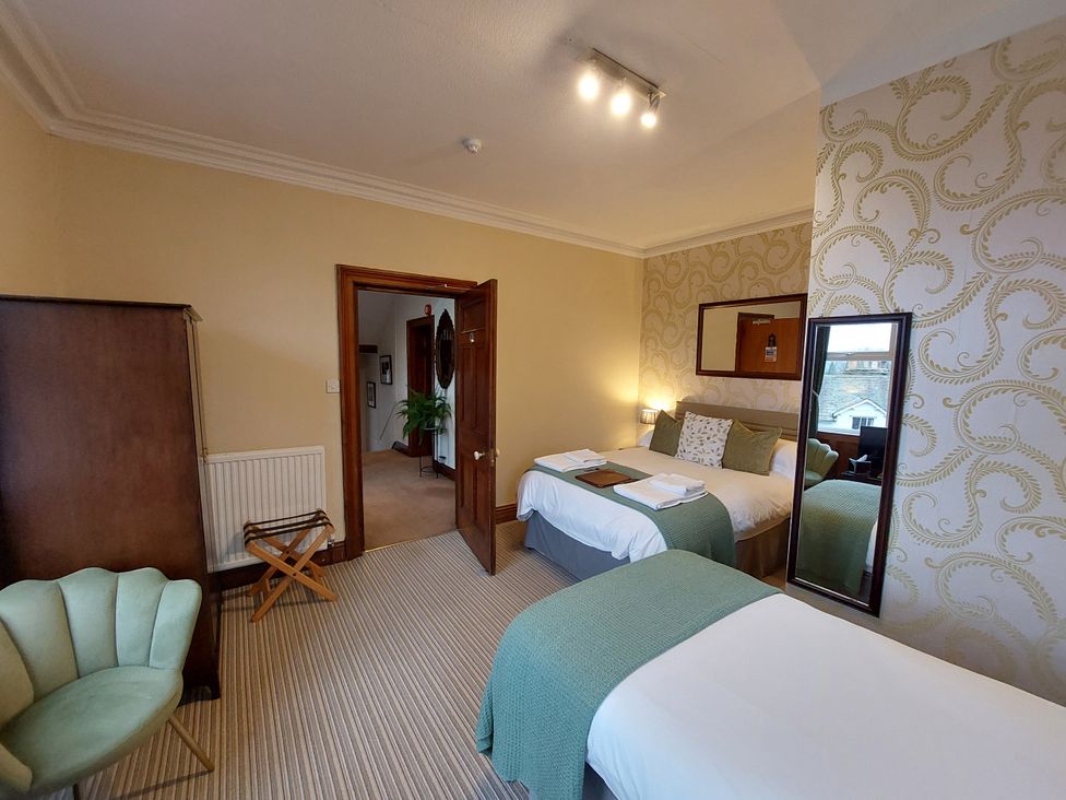 A bedroom with two beds and a mirror at 1 Park Road in Windermere
