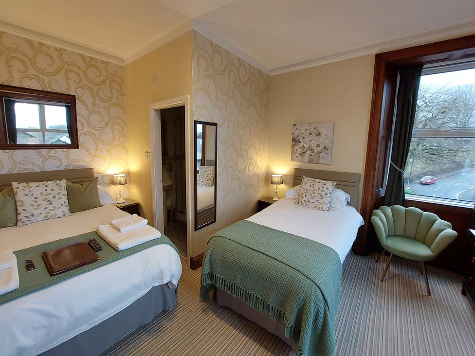 A bedroom with two beds and a window at 1 Park Road, Windermere
