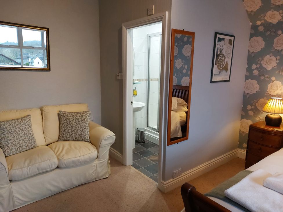 A bedroom with a sofa and adjacent bathroom at 1 Park Road in Windermere