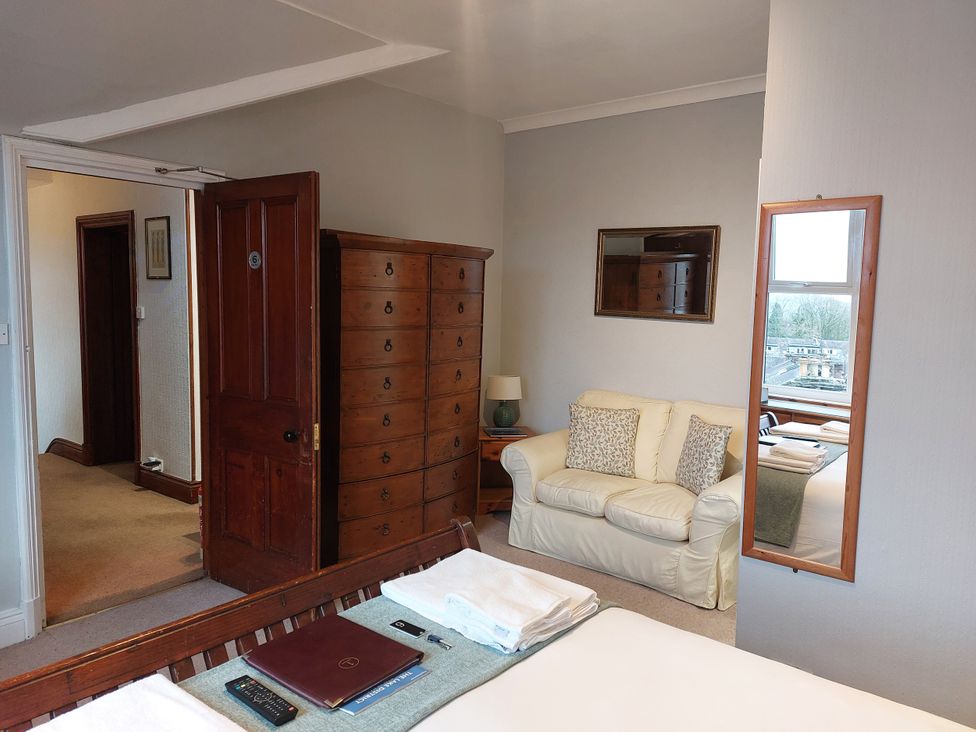 A bedroom with a bed, wardrobe, sofa and window at 1 Park Road, Windermere
