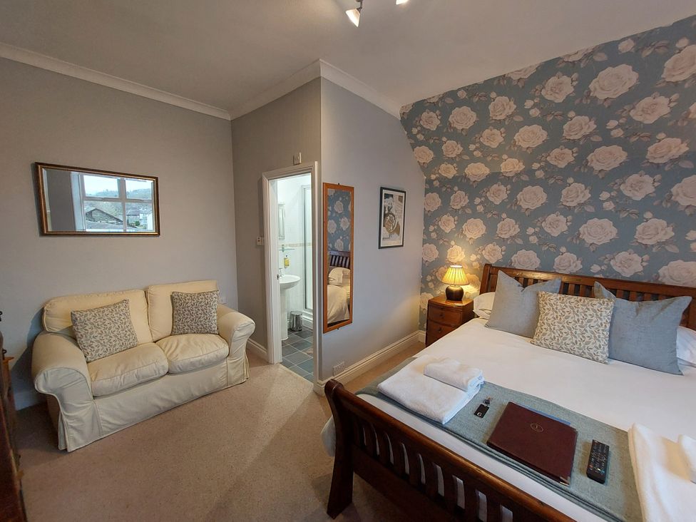 A bedroom with a bed and a sofa at 1 Park Road in Windermere