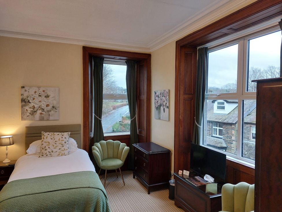 A bedroom with a bed, lamp, and window at 1 Park Road in Windermere