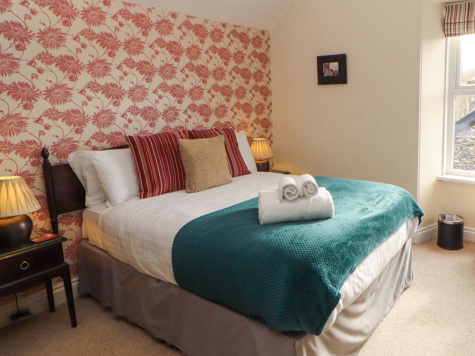 A bedroom with a bed, lamp, and window at 1 Park Road in Windermere