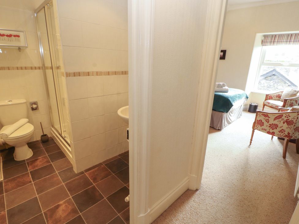A bathroom with toilet and shower connected to a bedroom at 1 Park Road Windermere