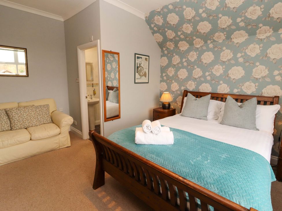 A bedroom with a bed and a sofa at 1 Park Road in Windermere