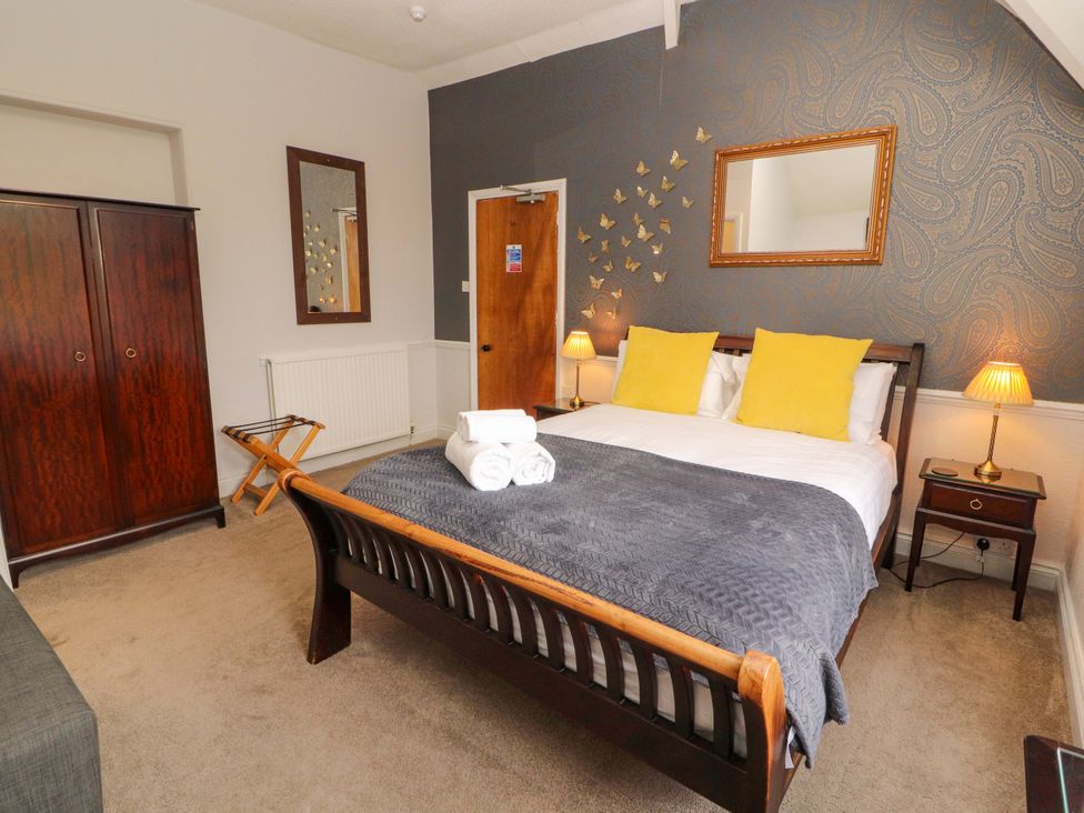 A bedroom with a double bed and wooden furniture at 1 Park Road in Windermere