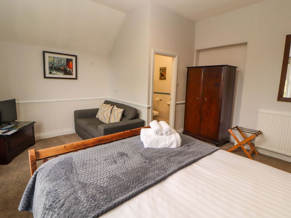 A bedroom with a bed, sofa, and television at 1 Park Road, Windermere