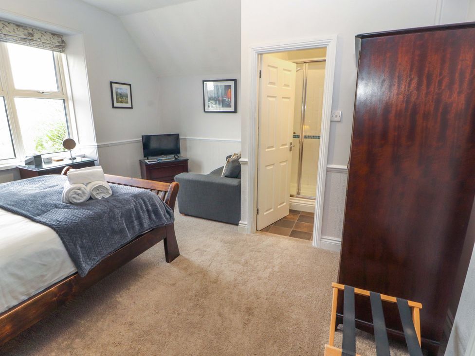 A bedroom with a bed, sofa, and television at 1 Park Road, Windermere