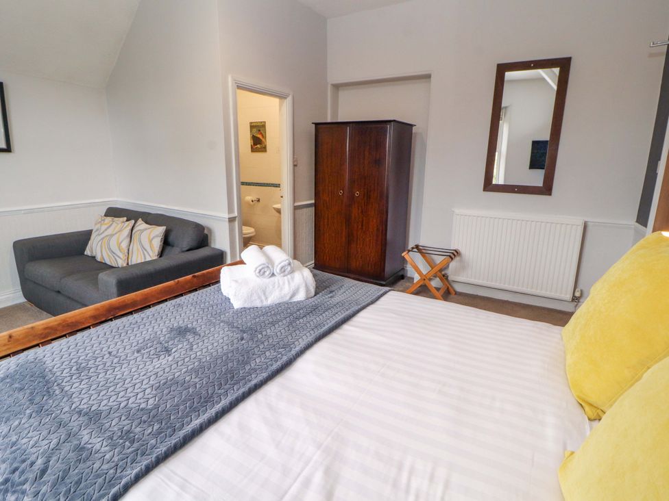 A bedroom with a bed, sofa, and wardrobe at 1 Park Road in Windermere