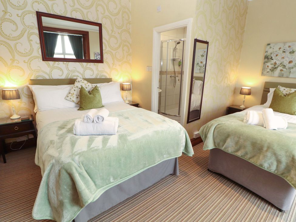 A bedroom with two beds and a shower at 1 Park Road in Windermere