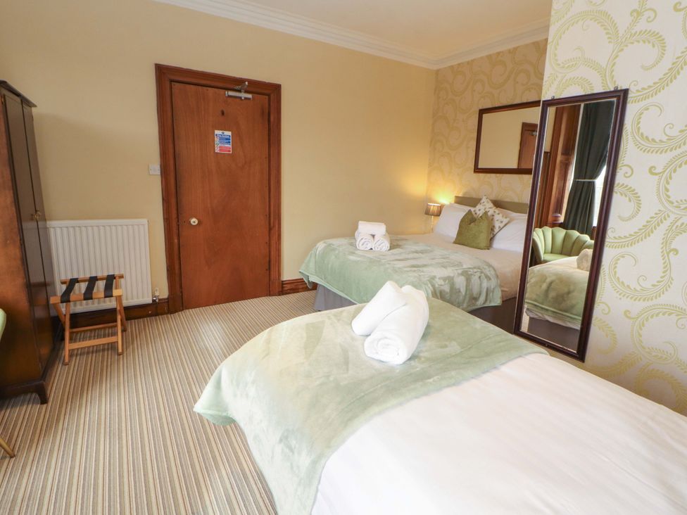 A bedroom with two beds and a large mirror at 1 Park Road Windermere
