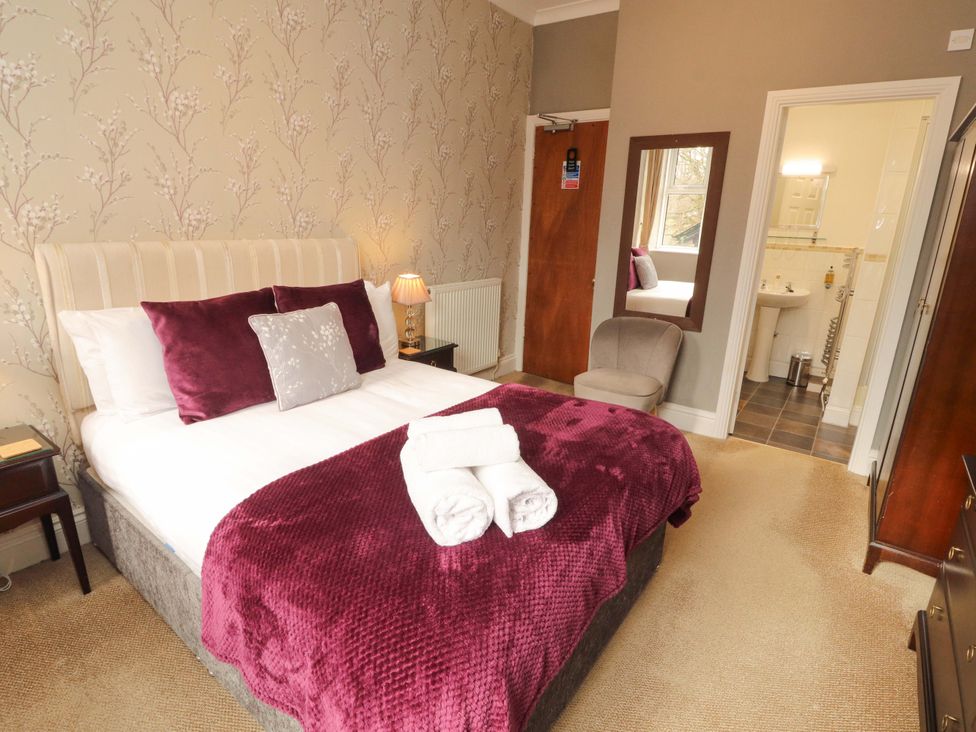 A bedroom with a bed, chair and bathroom at 1 Park Road Windermere