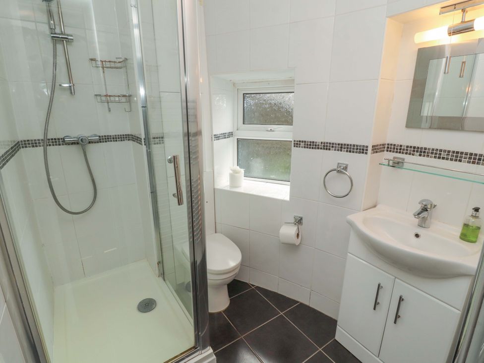 A bathroom featuring a shower, toilet, and sink at 1 Park Road in Windermere