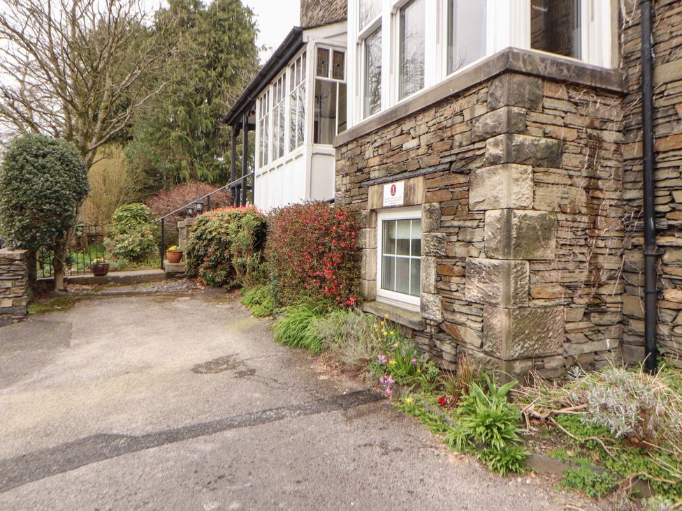 A house with a stone wall and bushes at 1 Park Road in Windermere