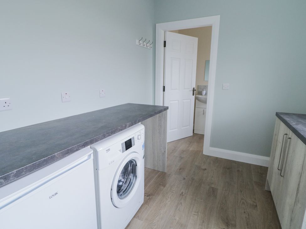 A laundry room with a washing machine and fridge at teac Caoimhe in Falcarragh