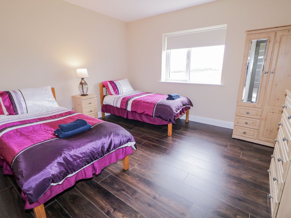 A bedroom with two beds and a wardrobe at Teac Caoimhe in Falcarragh