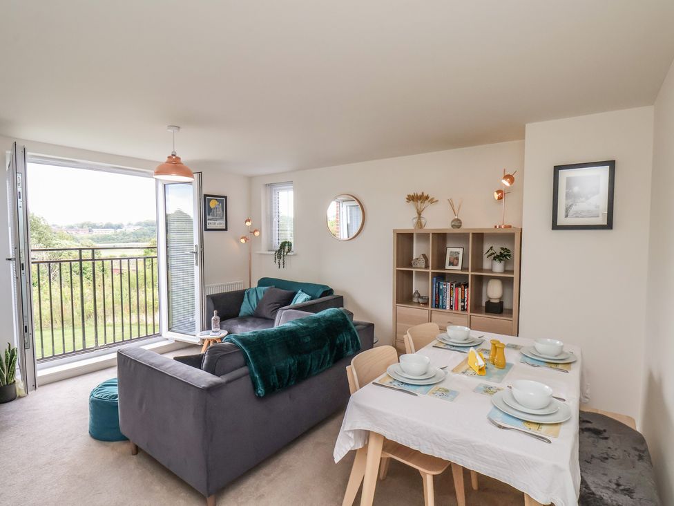 A living room with a dining area and bookshelf at Larpool Retreat