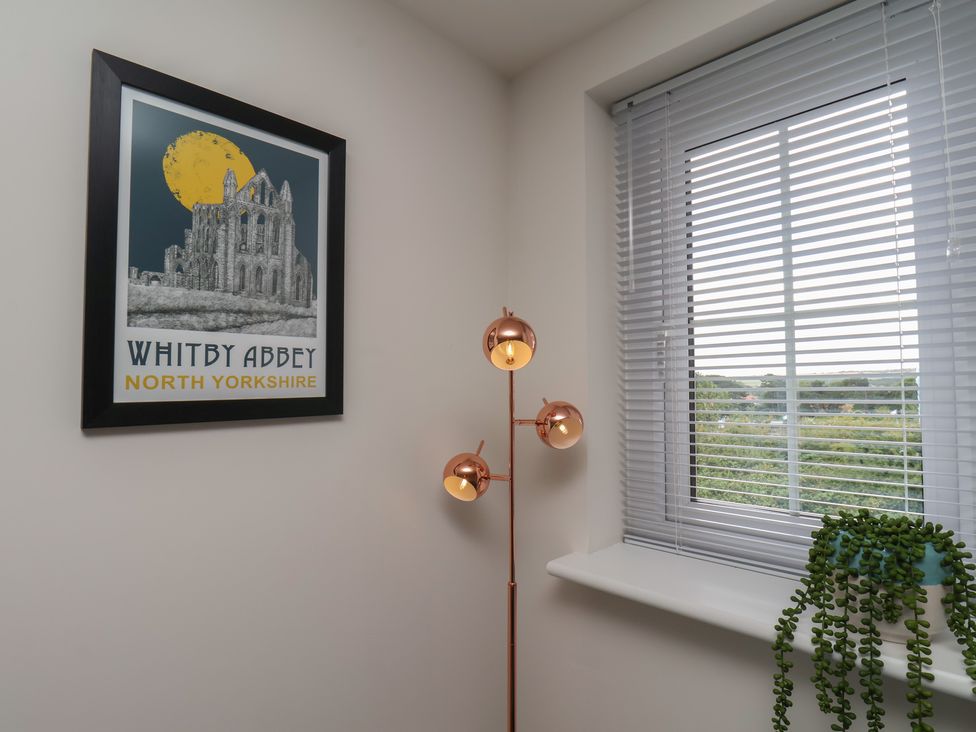 A room featuring a poster, floor lamp, window, and plant at Larpool Retreat
