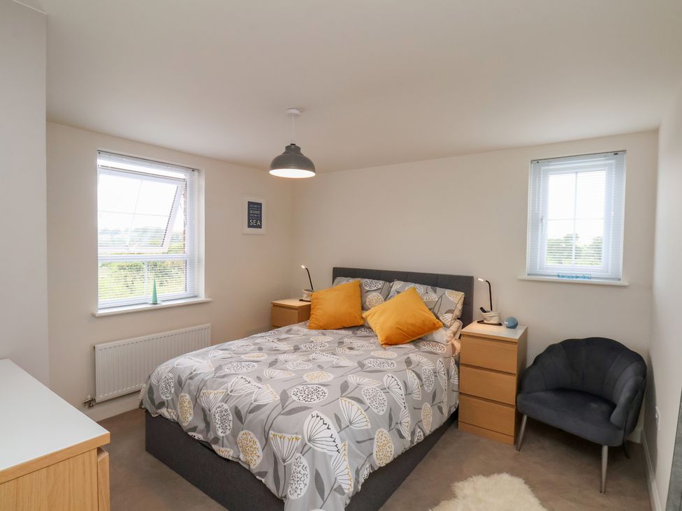 A bedroom with a bed and two windows at Larpool Retreat