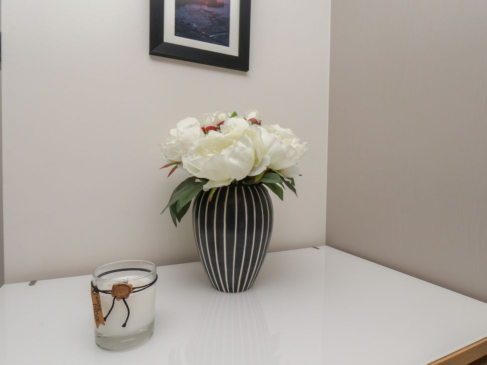 A table with a vase of artificial flowers and a candle at Larpool Retreat in Whitby