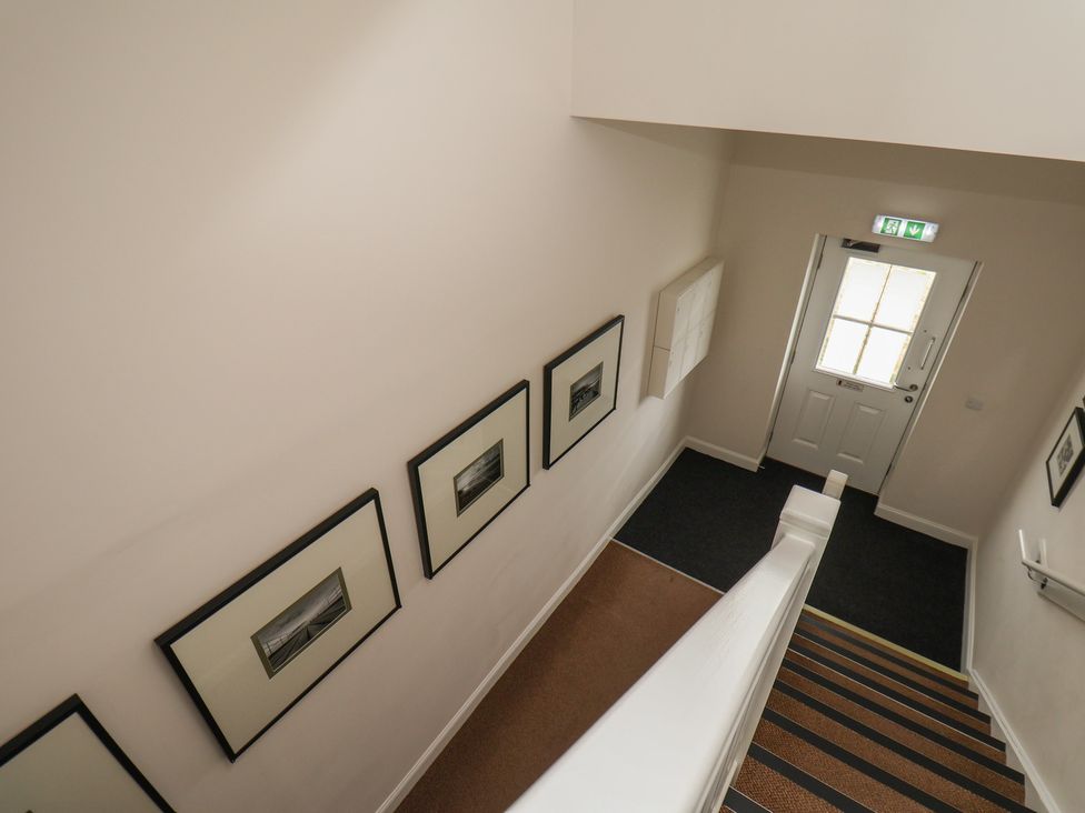 A staircase with pictures on the wall and a door at Larpool Retreat in Whitby