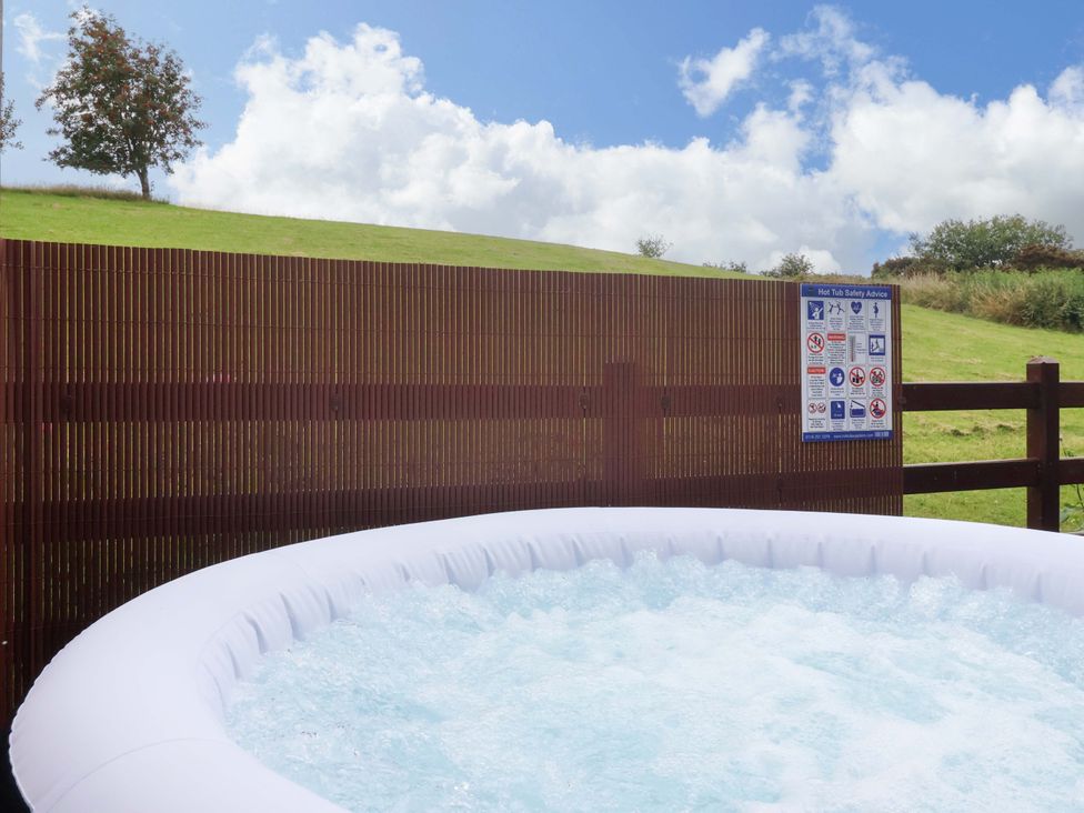 A hot tub with a safety sign and a fence in a grassy area at Badgers Retreat - Two Dales in Richmond