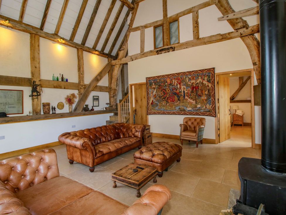 A living room with leather sofas, tapestry, and wooden beams at Crook Barn in Tenbury Wells