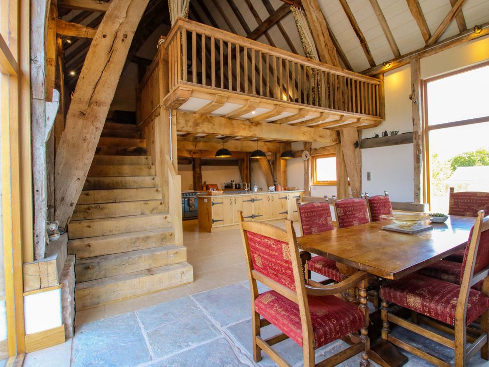 A dining room with a staircase and kitchen in view at Crook Barn Tenbury Wells