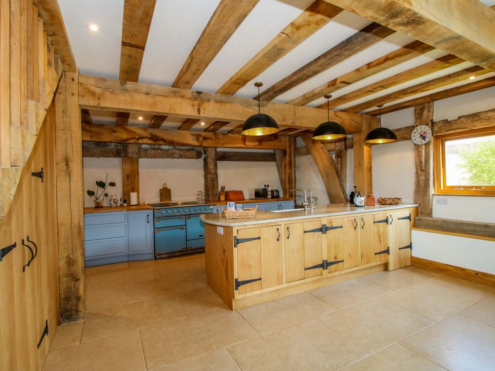A kitchen with wooden cabinets and a stove at Crook Barn in Tenbury Wells
