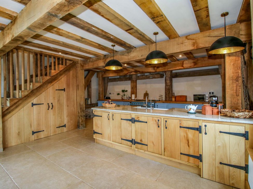 A kitchen with wooden cabinets and an island at Crook Barn in Tenbury Wells
