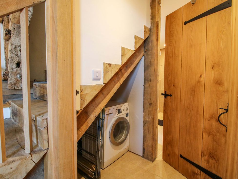 A utility room with a washing machine and stairs at Crook Barn Tenbury Wells