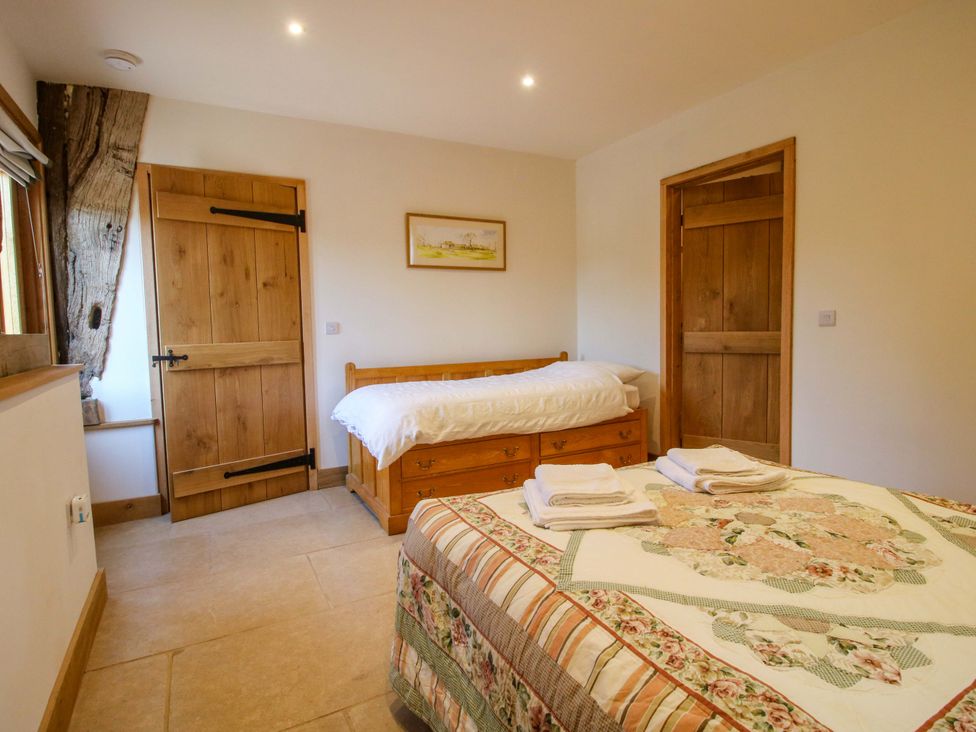 A bedroom with two beds and wooden furniture at Crook Barn in Tenbury Wells