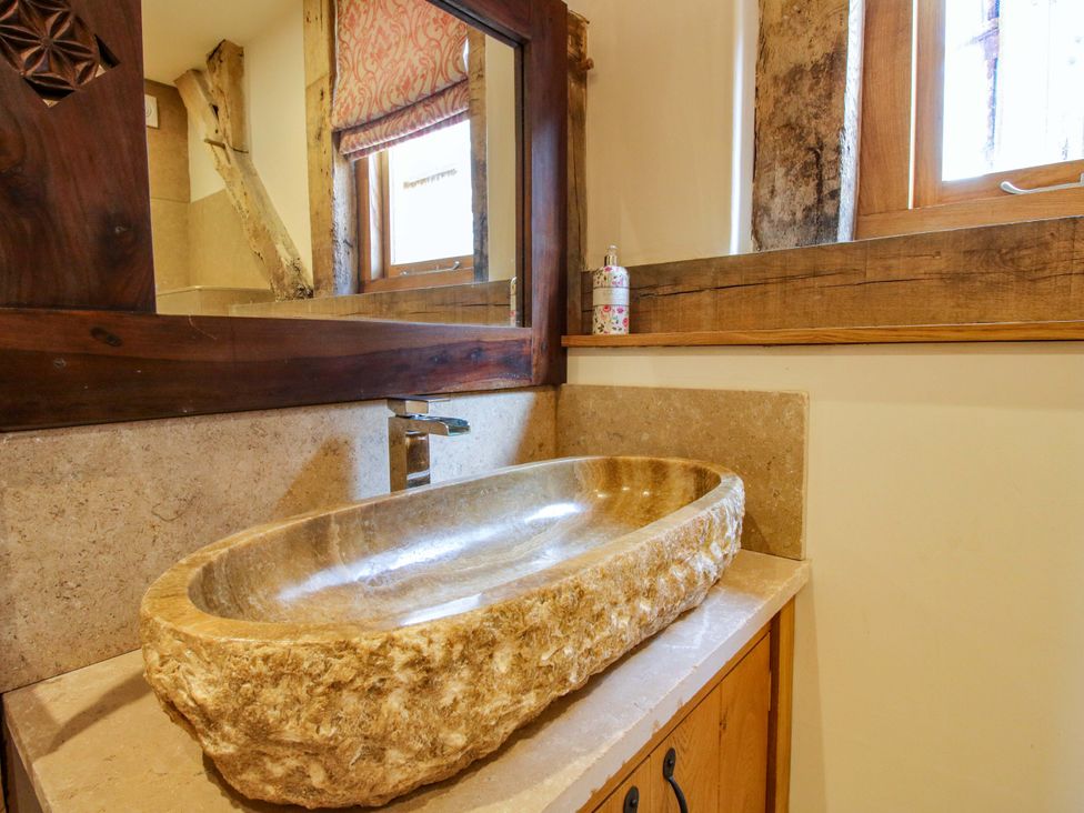 A bathroom with a stone sink and wooden elements at Crook Barn in Tenbury Wells